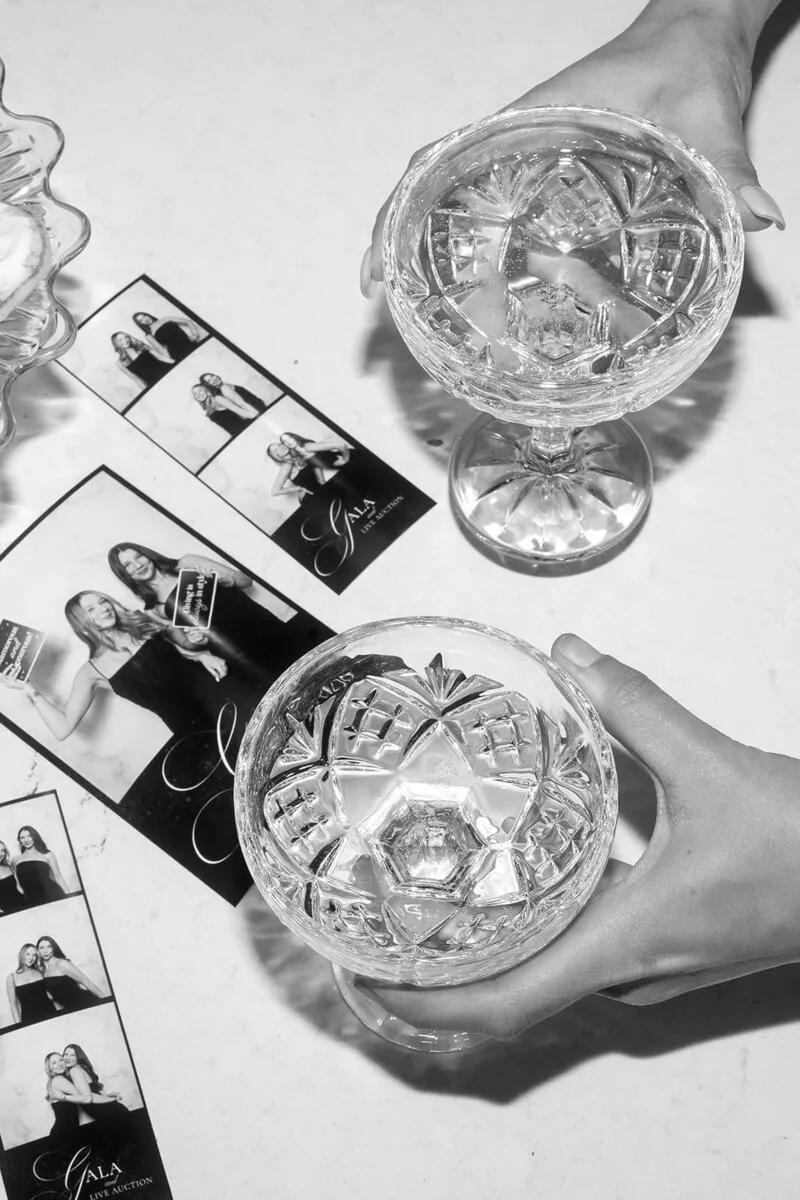 A hand holding a coupe beside printed photo strips